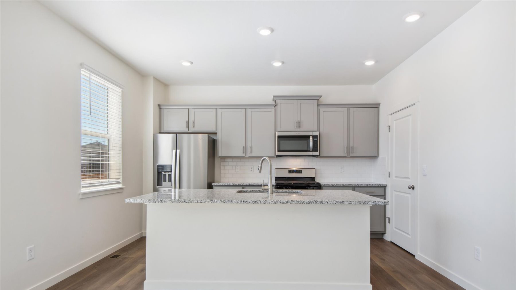 LED lighting, ample cabinetry with crown molding, and front view of large kitchen island featuring built-in sink