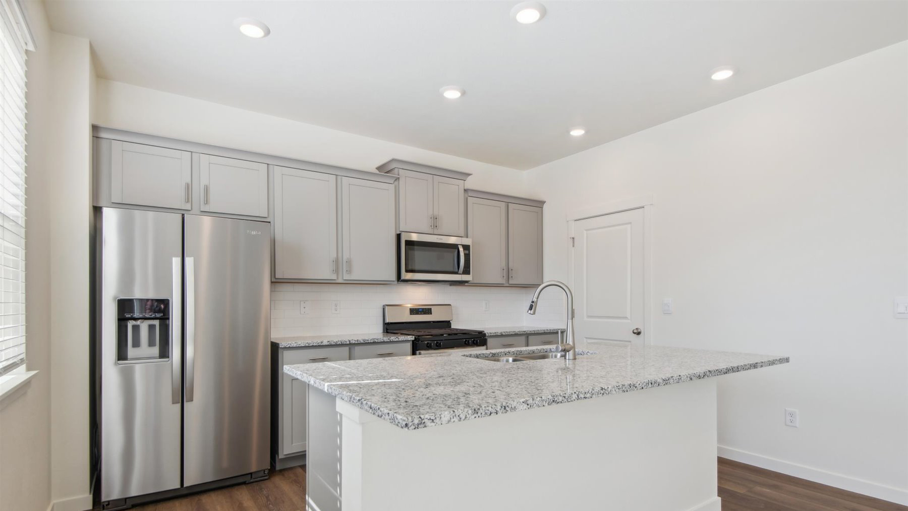 Angled view of kitchen showing cabinet storage space, pantry, granite countertops, and soft LED lighting