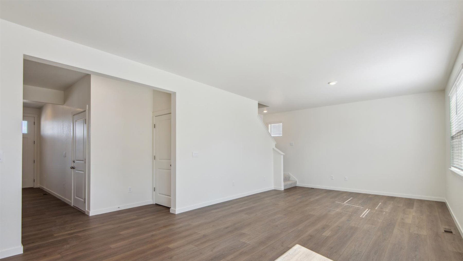 Living area with integrated great room and dining, upper floor stairwell, storage, and hallway door leading to garage