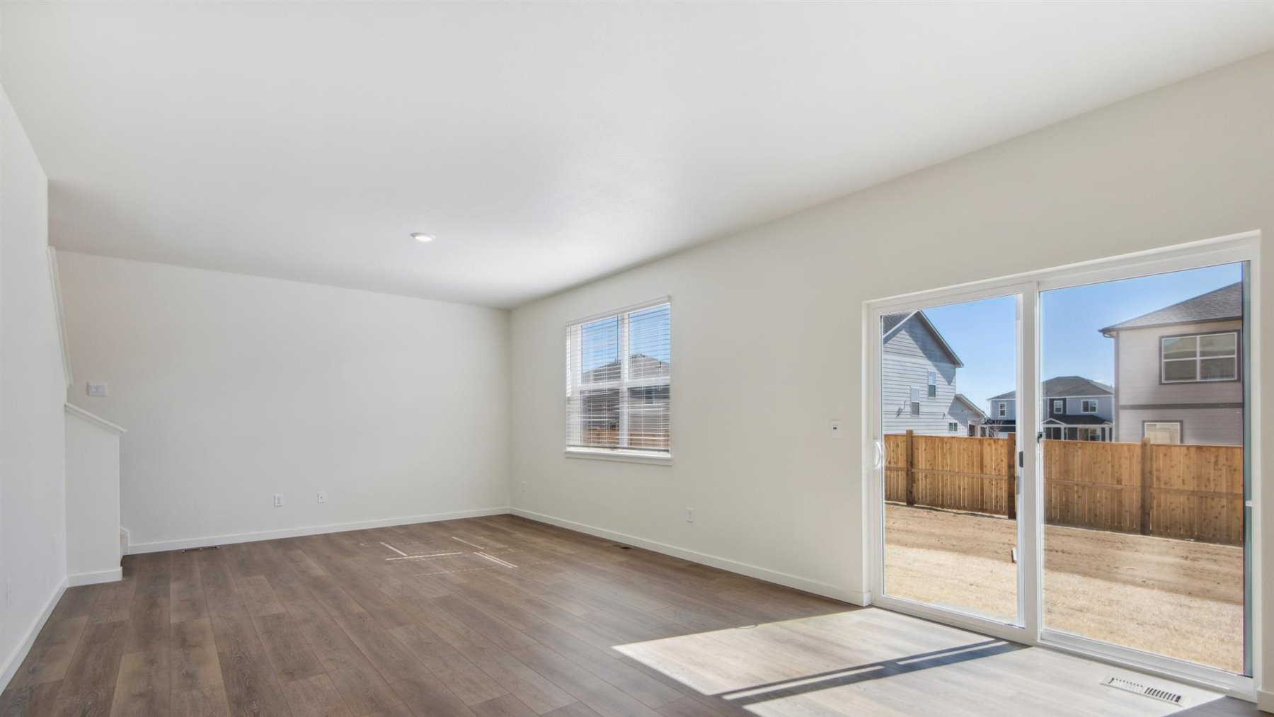 Great room with window and staircase to upstairs, dining nook with outdoor access from sliding patio door