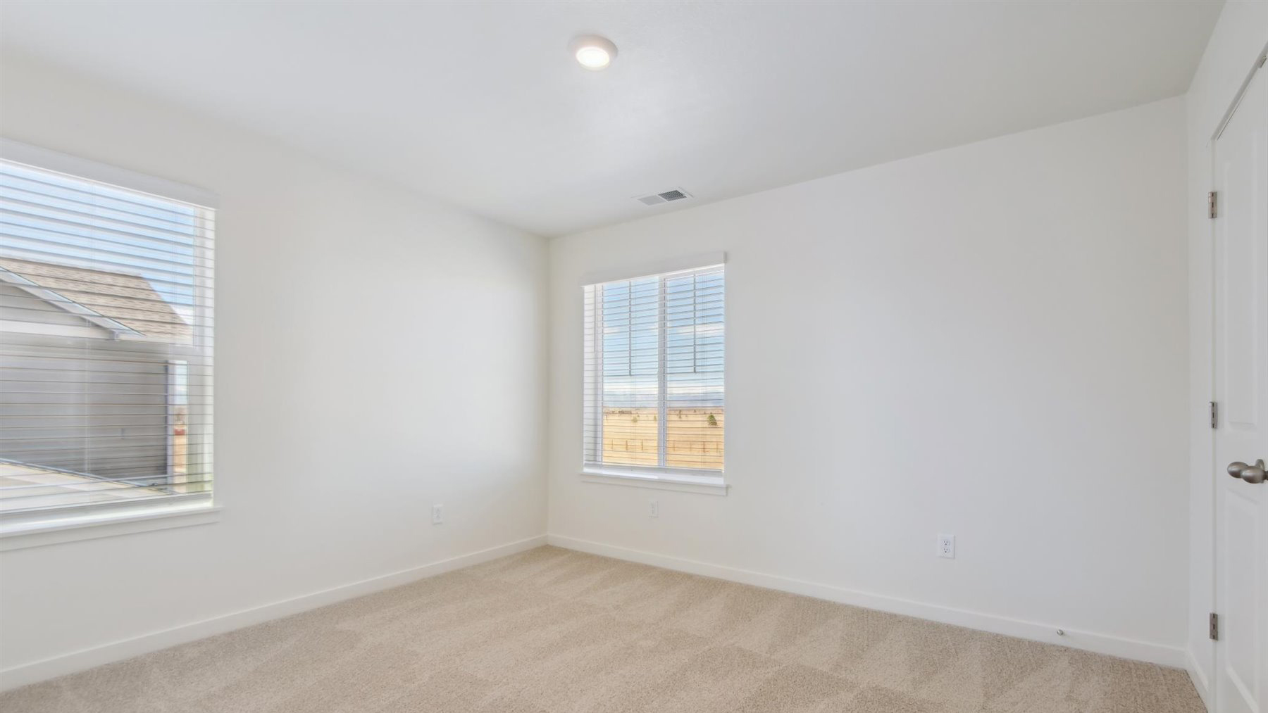 Secondary bedroom adjacent to primary bedroom with two windows for ample lighting