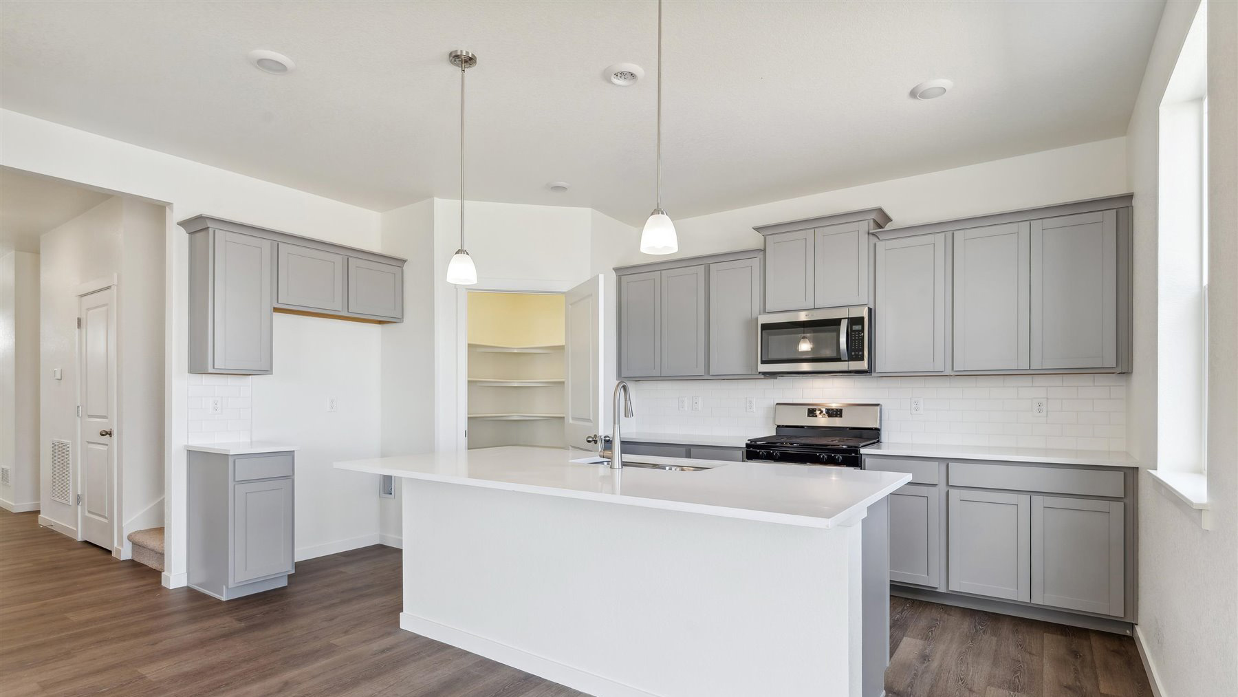 Alternate view of kitchen showing ample cabinet storage, corner pantry, and center island