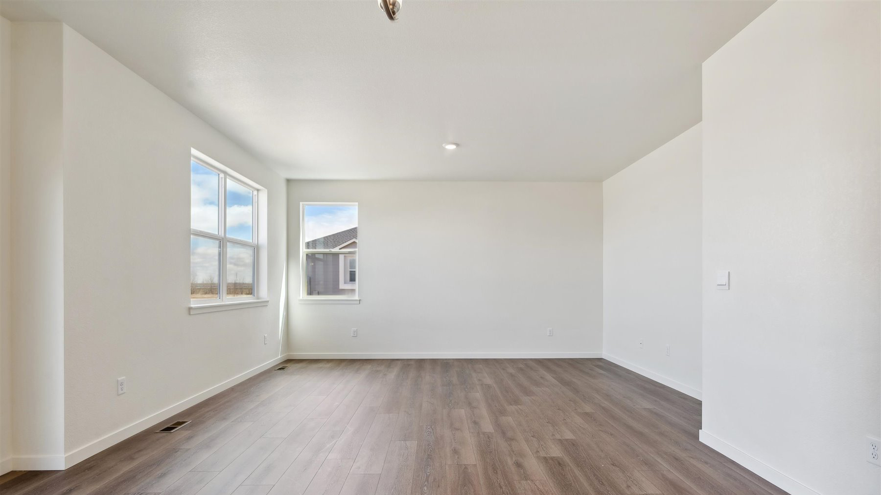 View from kitchen into connected dining area and great room showing ample natural lighting from windows