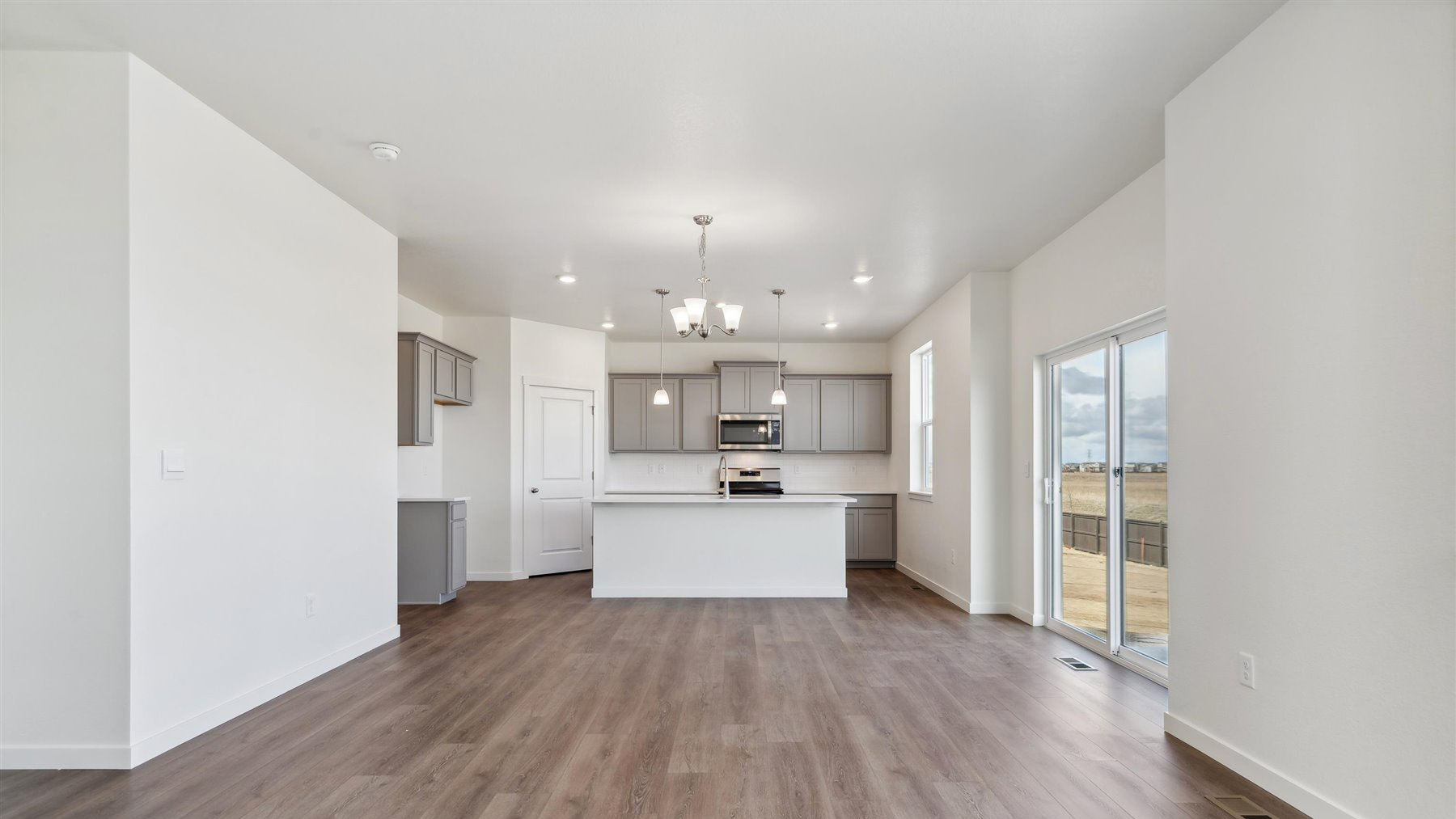View from great room into dining area and kitchen featuring ample lighting from LED fixtures and sliding patio door