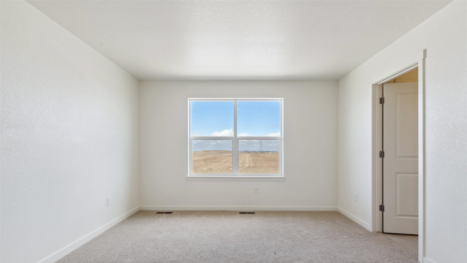 Primary bedroom on upper floor with large window, plush carpeting, and connected private bathroom