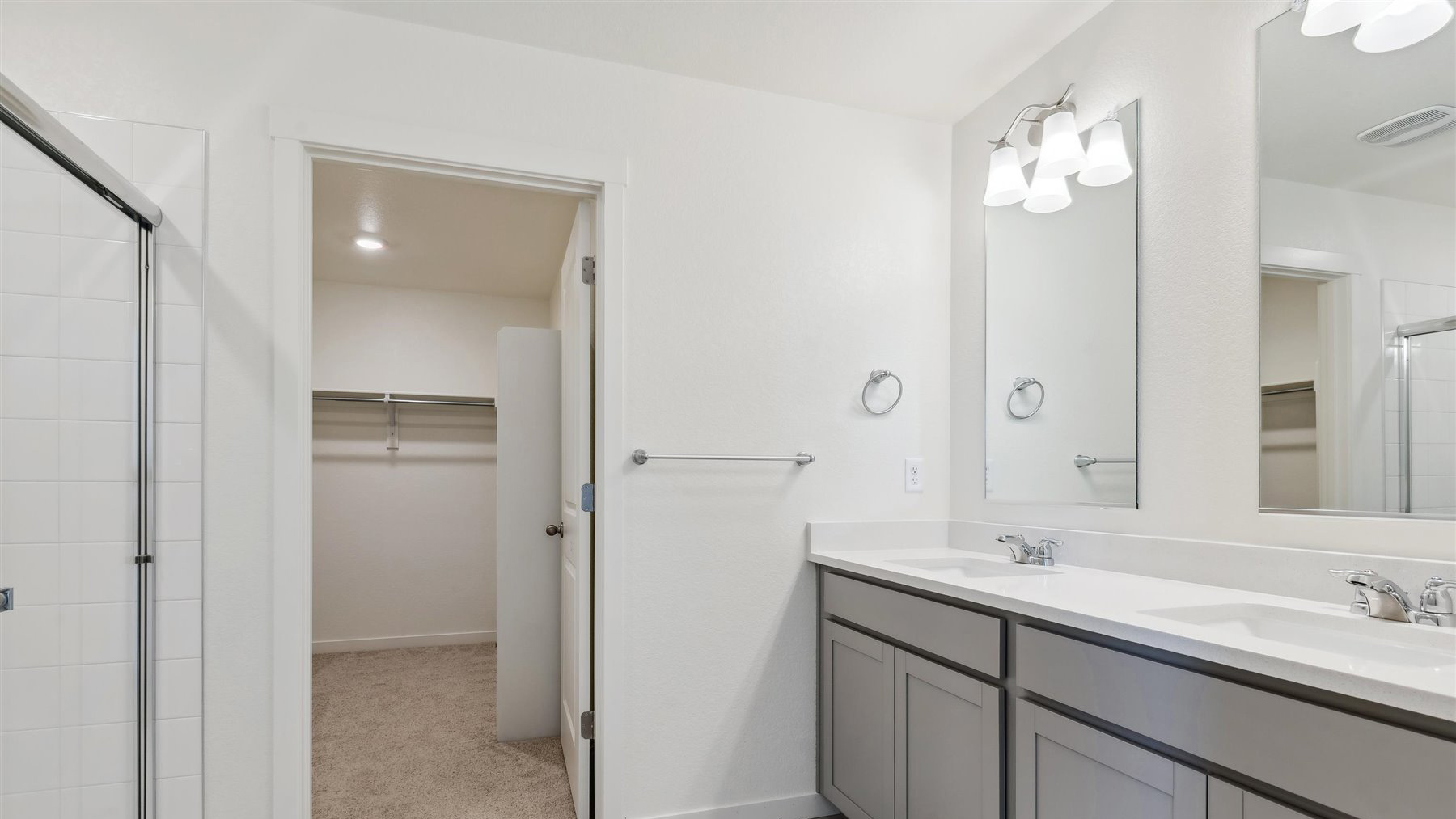 Private bath in primary bedroom suite featuring dual vanity sinks, ample granite counterspace, and spacious walk-in closet