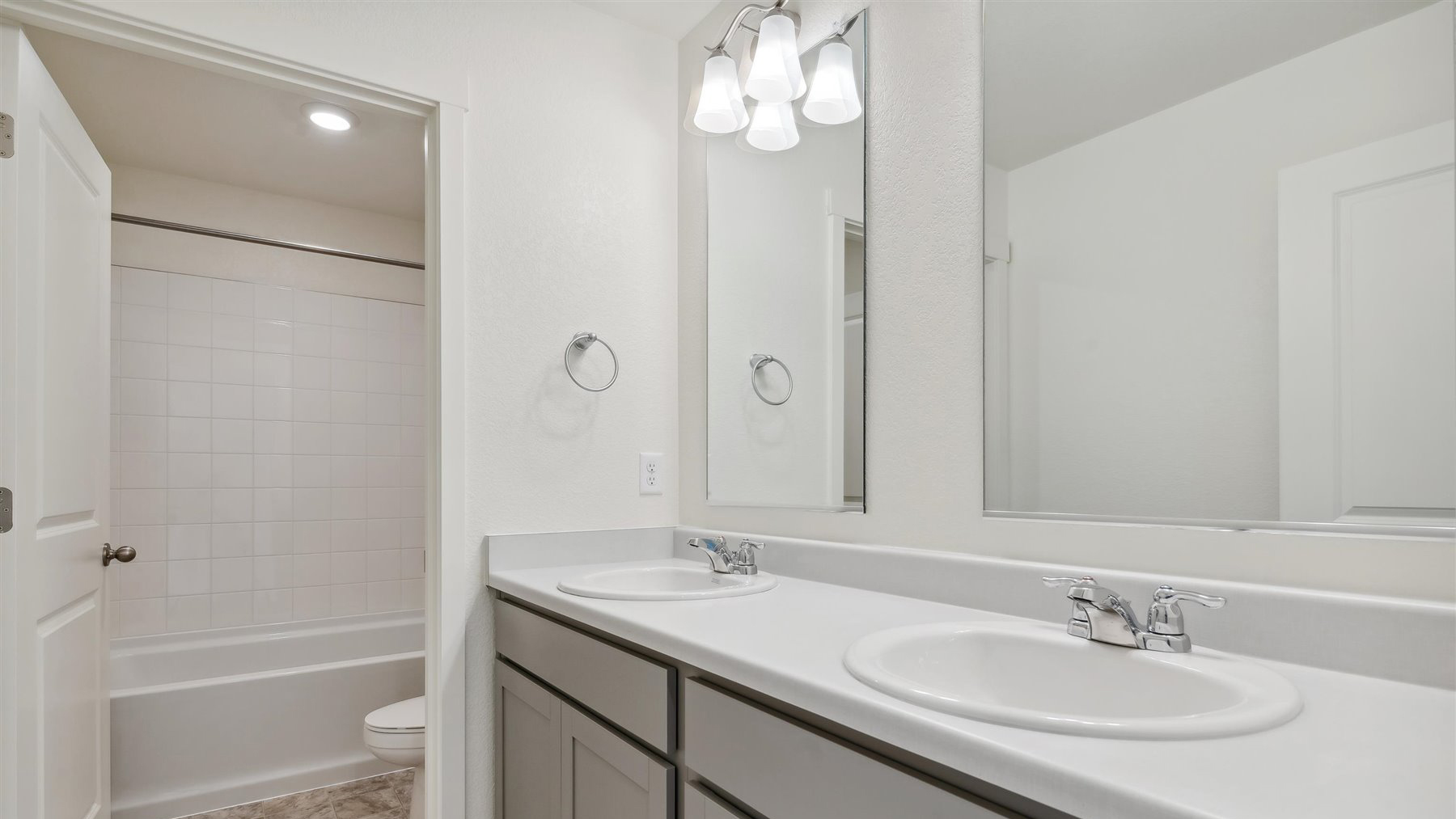 Split secondary upper floor bath with dual vanity sinks with separate area for shower/tub combo and toilet