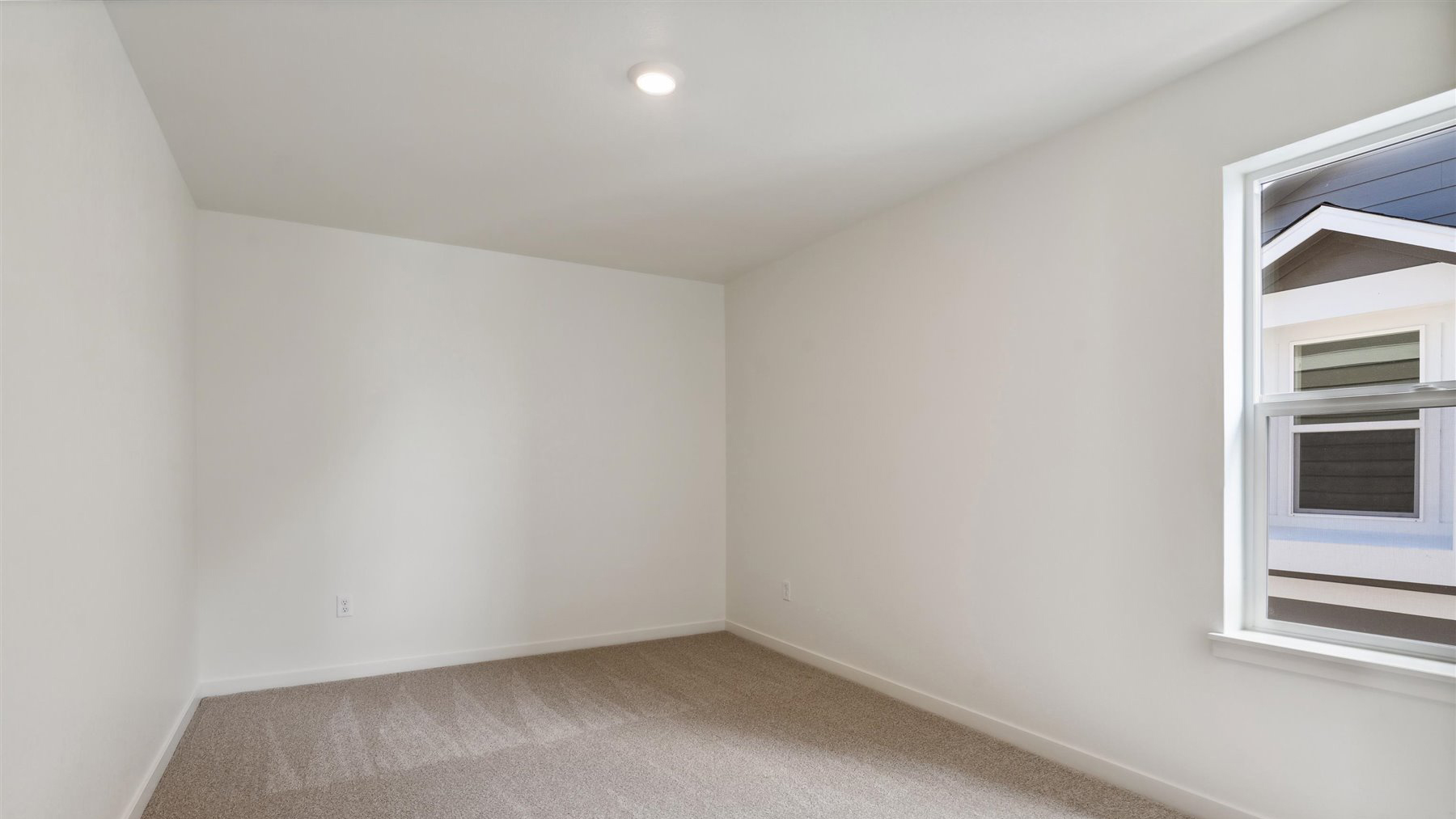 Another bedroom near laundry room with plush carpeting, a window, and energy efficient LED lighting