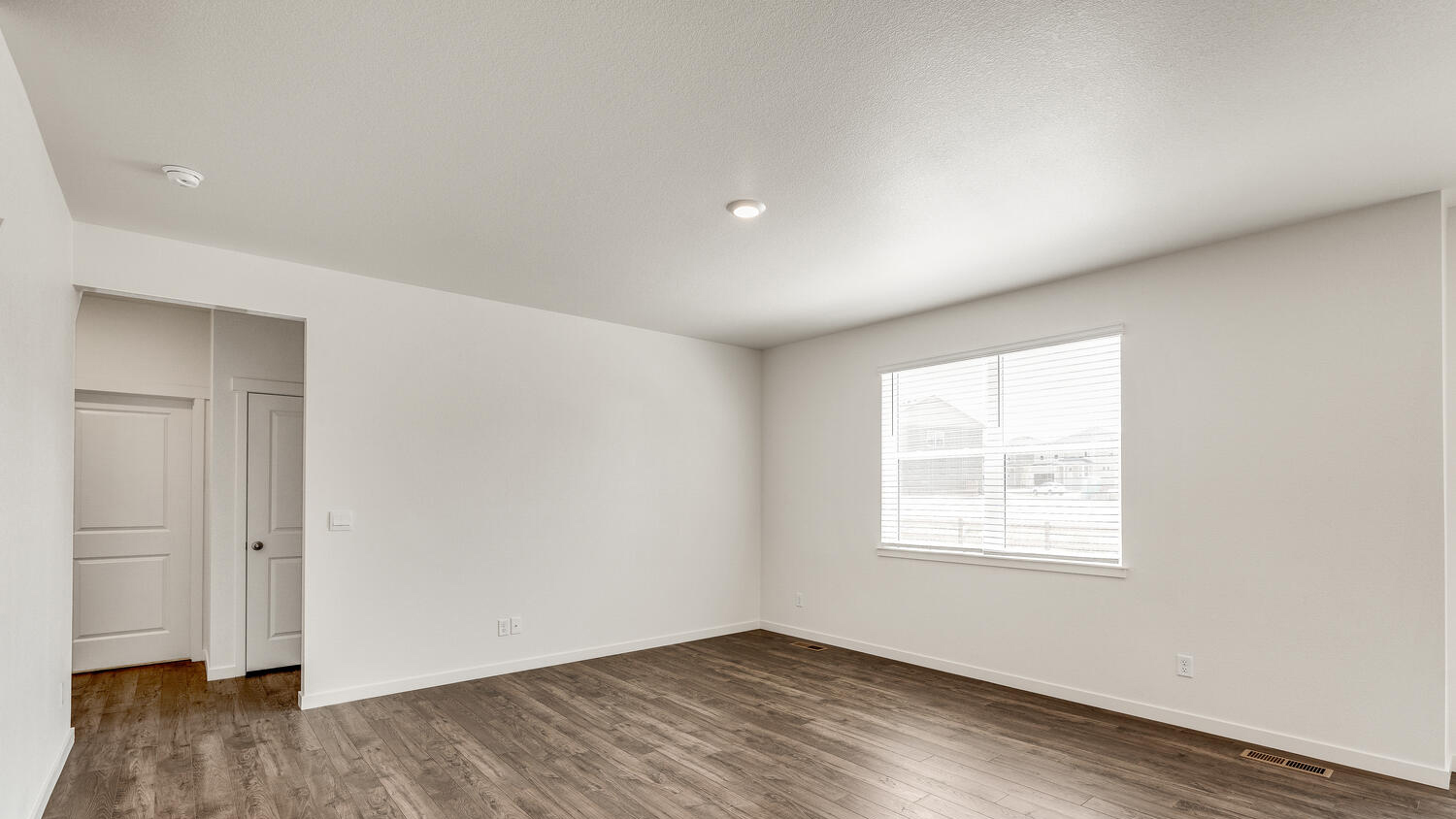 Alternate great room view featuring large window for ample natural lighting and opening to first floor bath and bedroom