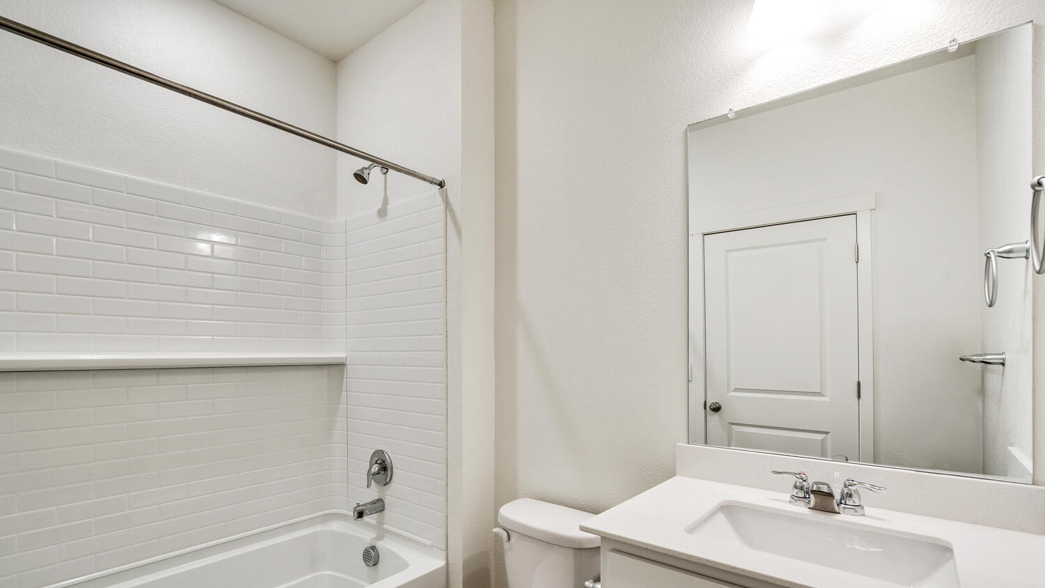 Main floor full bath with vanity lighting, chrome fixtures, and shower/tub combo
