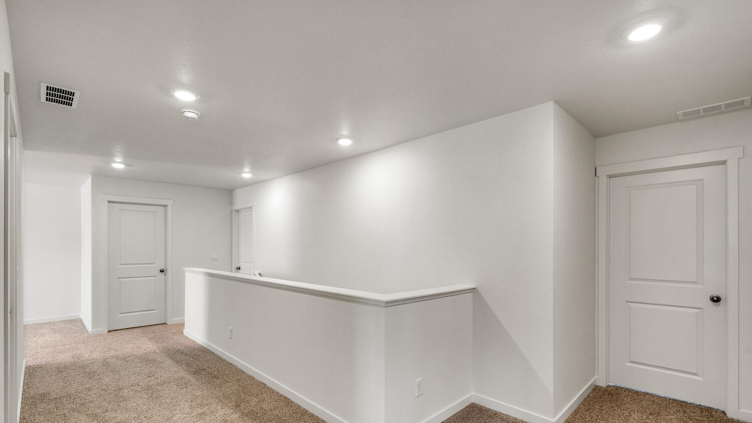 View of secondary bedroom door and upper floor stairwell leading to laundry room, primary bedroom suite, and living area