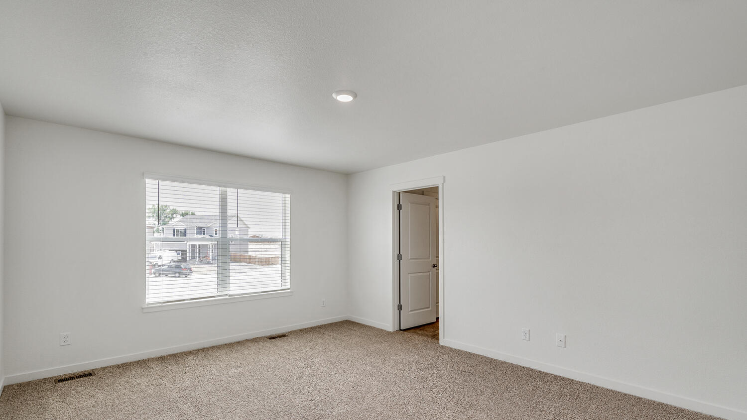 Alternate view of primary bedroom suite showing large window and entry to private bathroom
