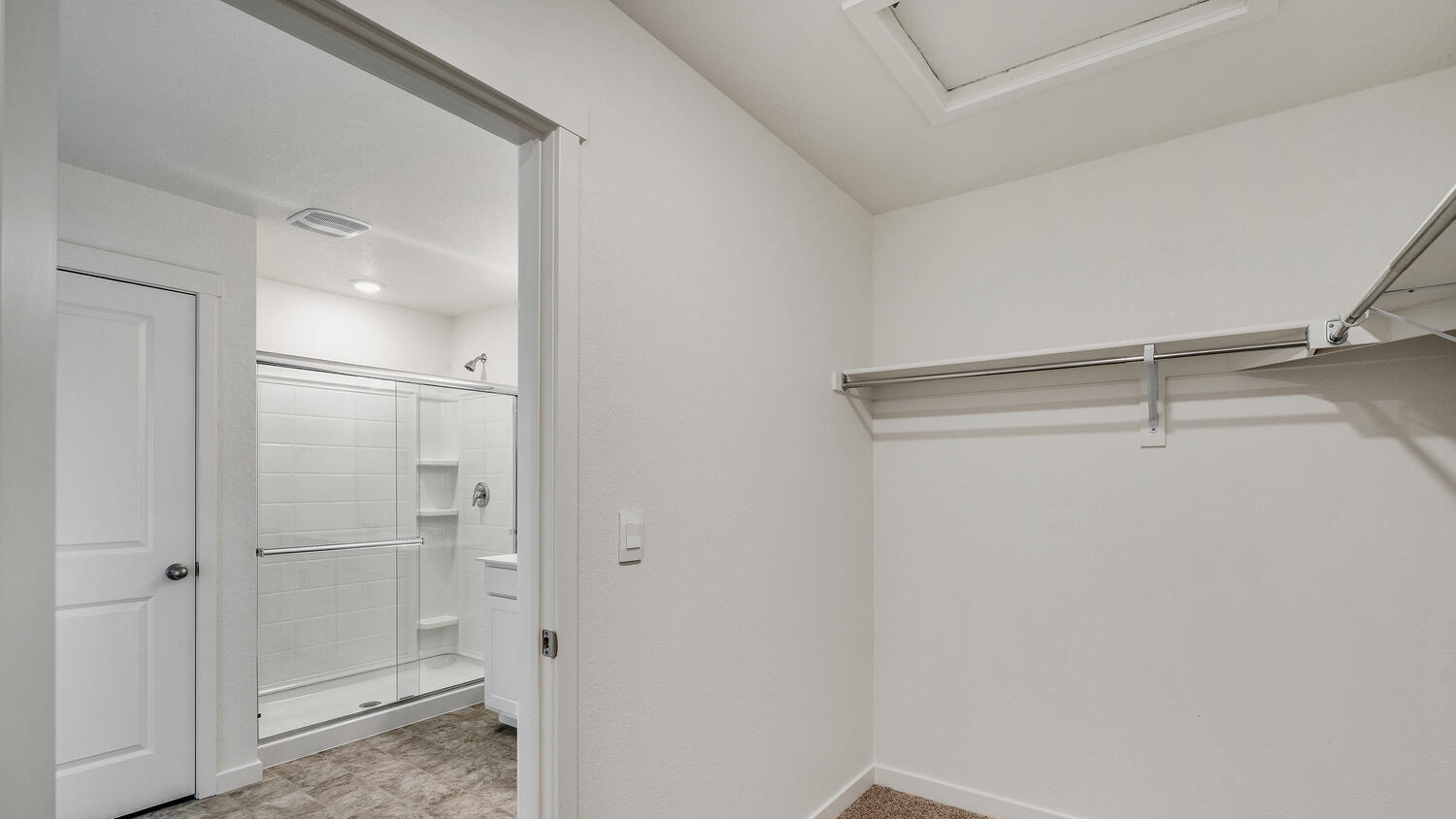 Walk-in closet connected to private bathroom with built-in shelving and linen storage