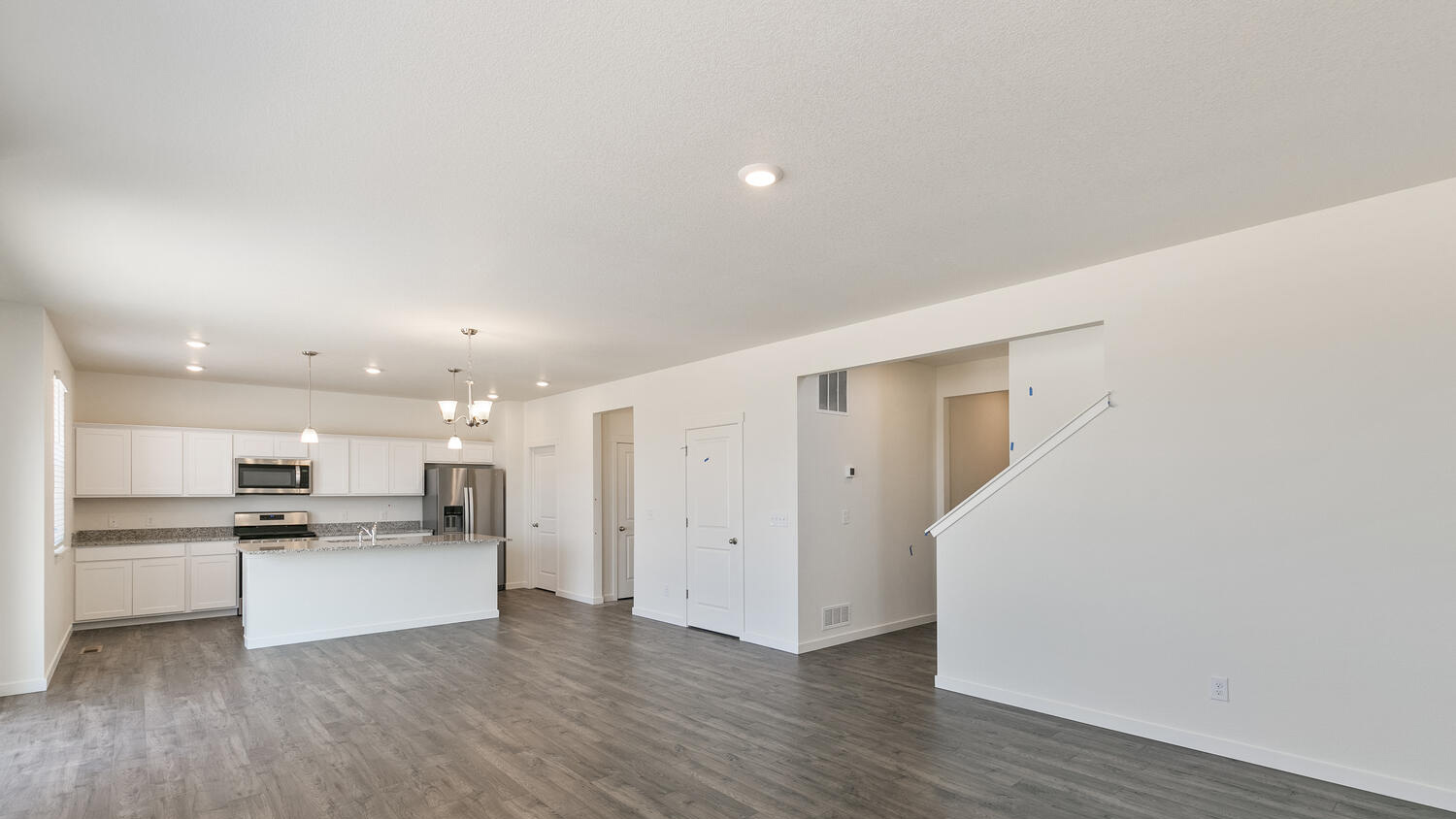 Alternate view of main living area and spacious open floor plan showing stairwell and opening to garage from kitchen