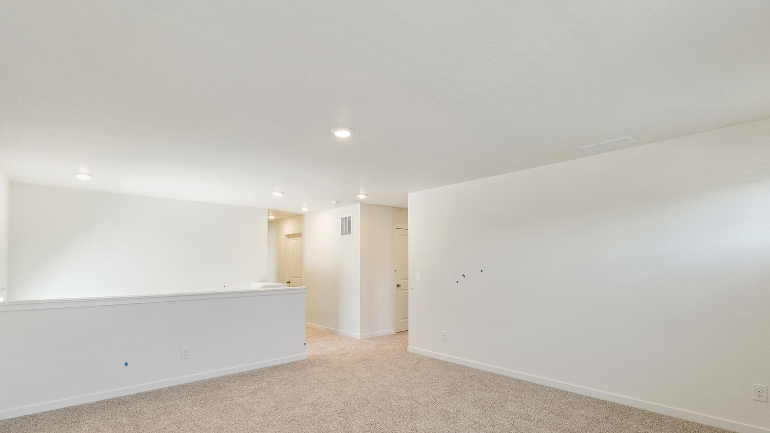 Top of stairwell showing generously sized upper floor living area with plush carpeting