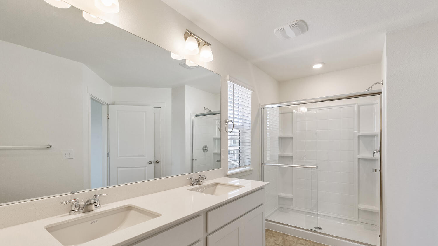 Angle view of primary bedroom private bath showing large counterspace, chrome fixtures, and ample lighting
