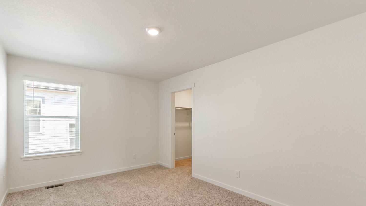 Secondary bedroom adjacent to laundry room on upper floor with window and walk-in closet