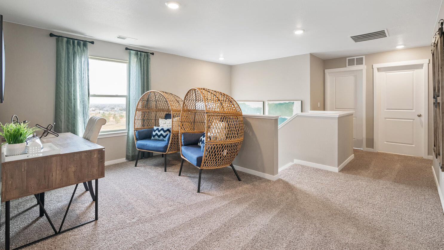 Upper floor loft area at top of stairwell with plush carpeting and ample lighting from window and LED light fixtures