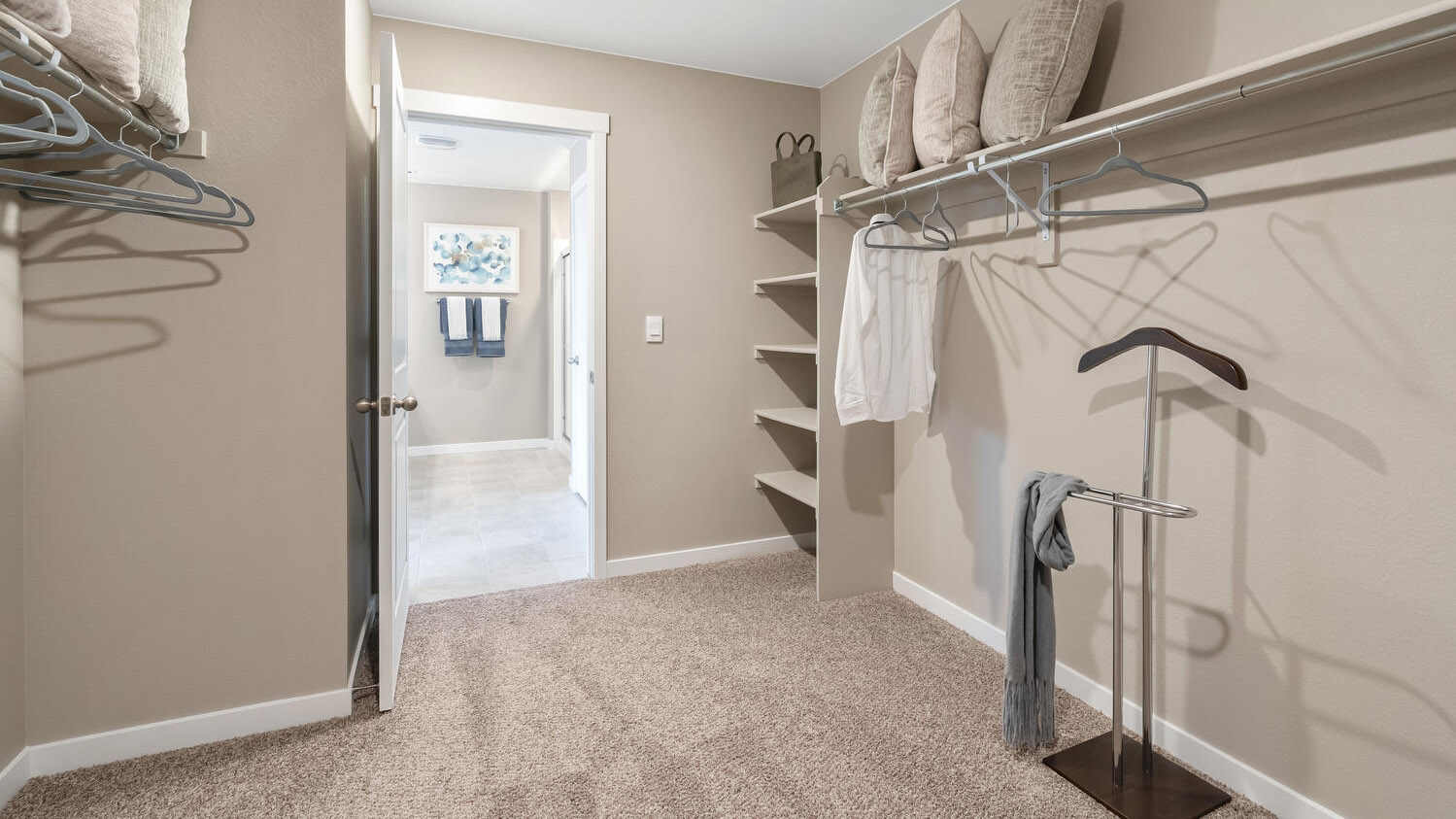 Spacious walk-in closet in primary bedroom suite with linen storage and built-in shelving