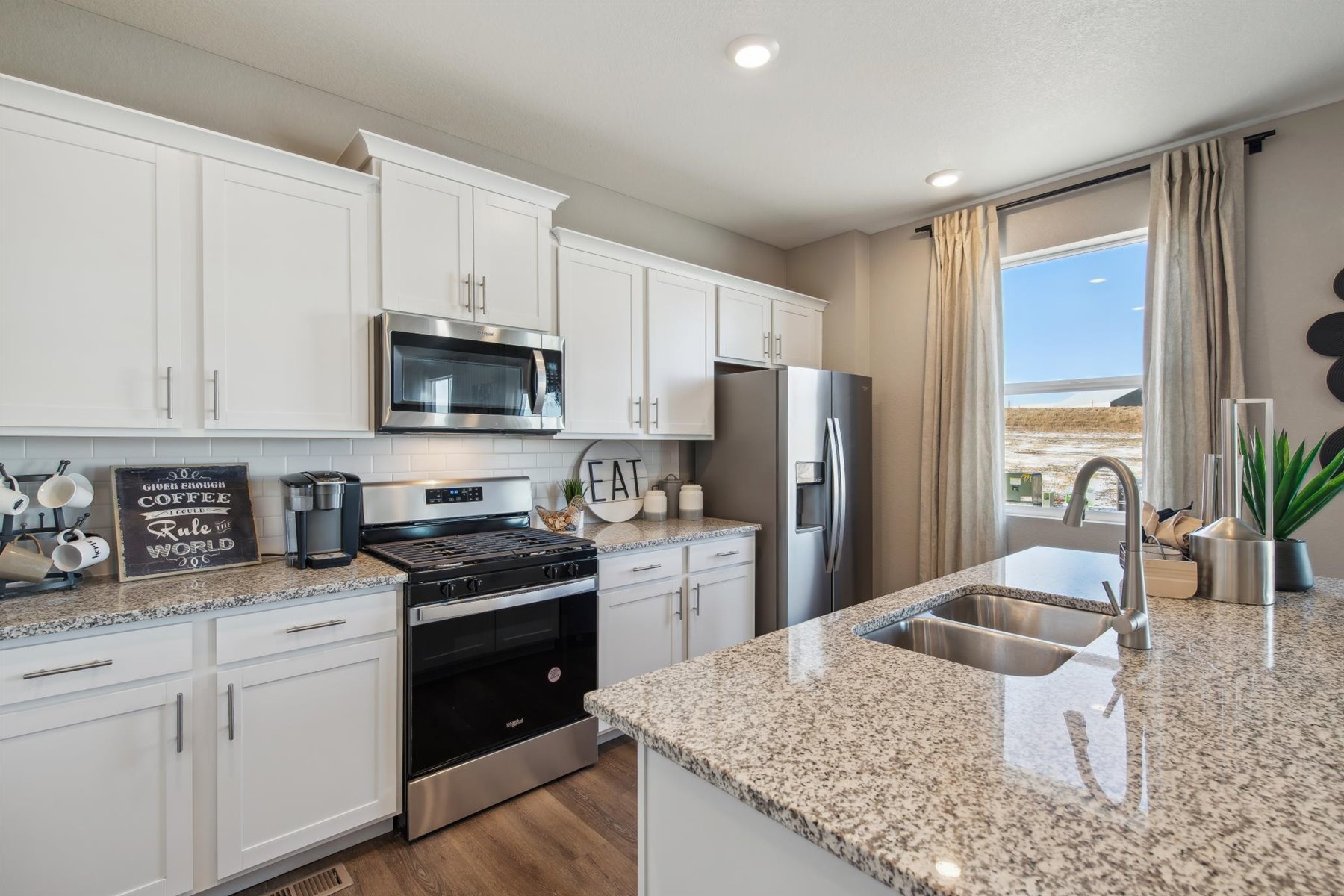 Ample kitchen cabinet storage, stainless steel appliances, built-in island sink, and window for additional natural light