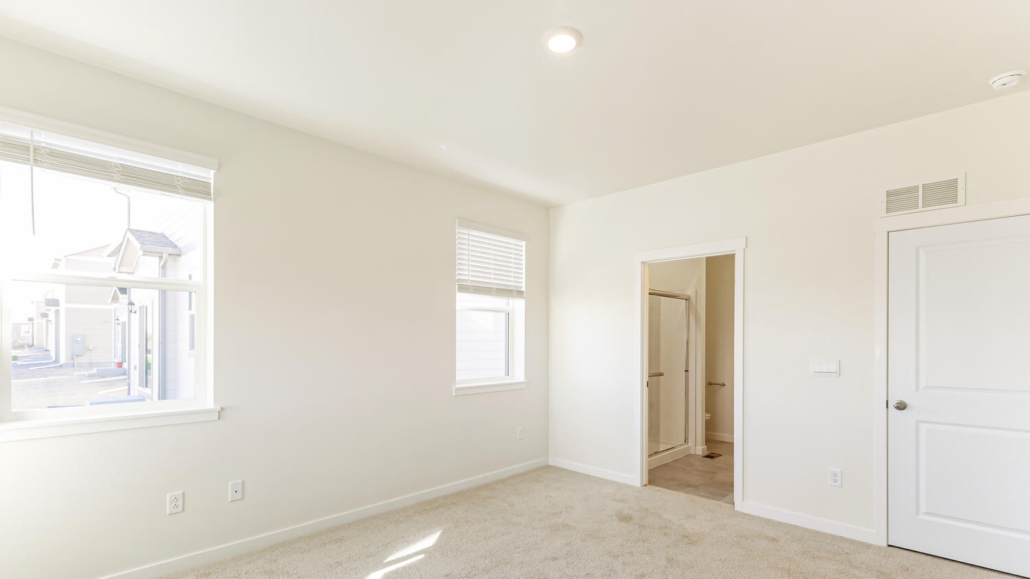 Alternate view of primary bedroom showing entrance to private bathroom