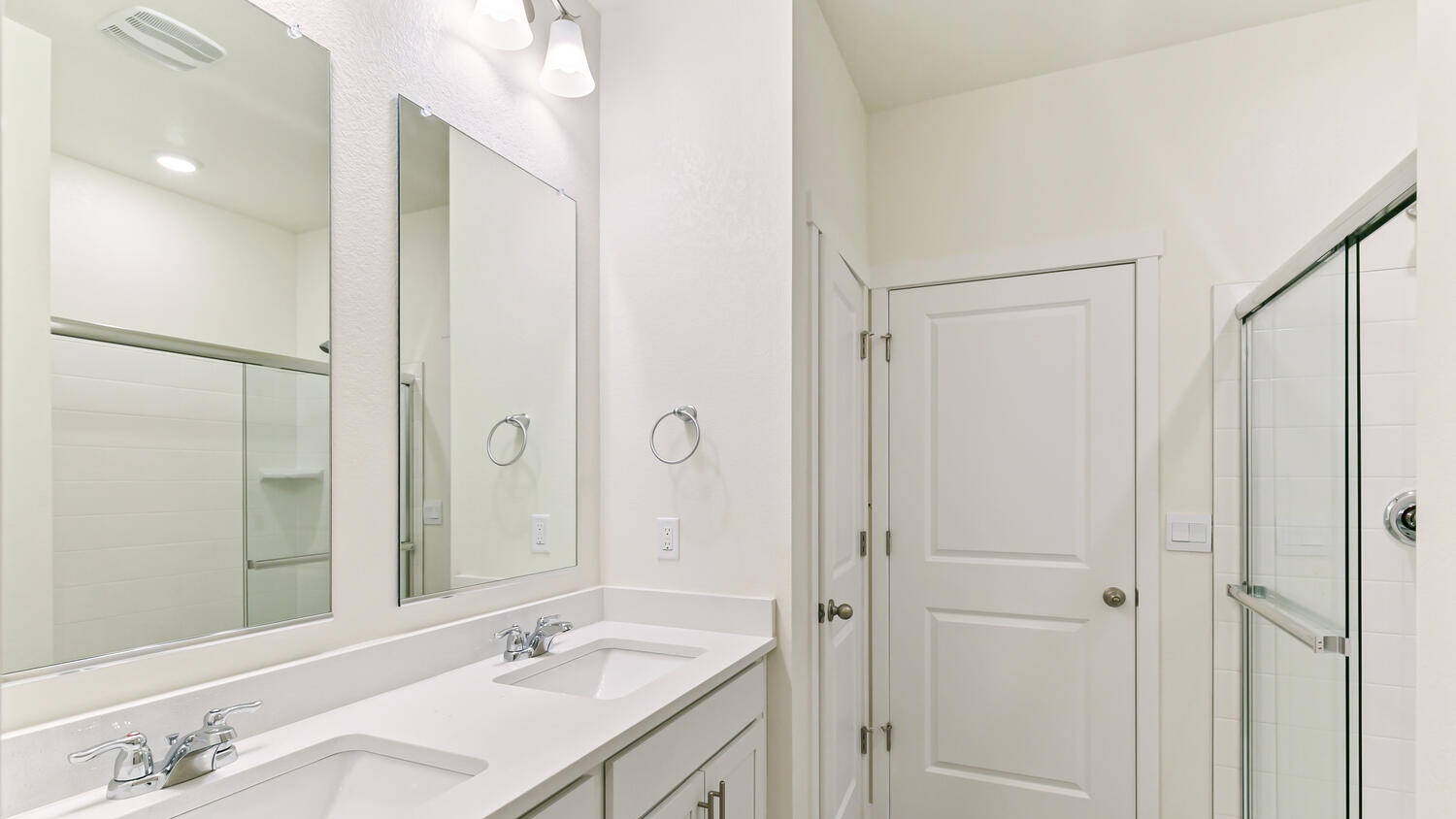 Private bath in primary bedroom suite with dual vanity sinks, linen closet, and step-in shower