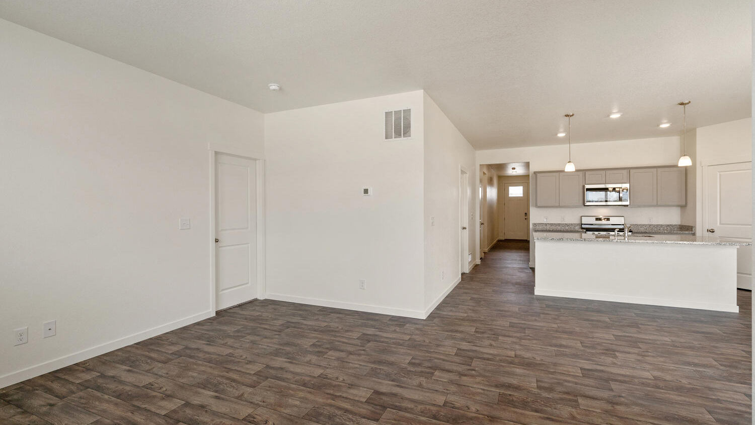 Open kitchen and great room showing 9' main level ceilings and door to primary bedroom