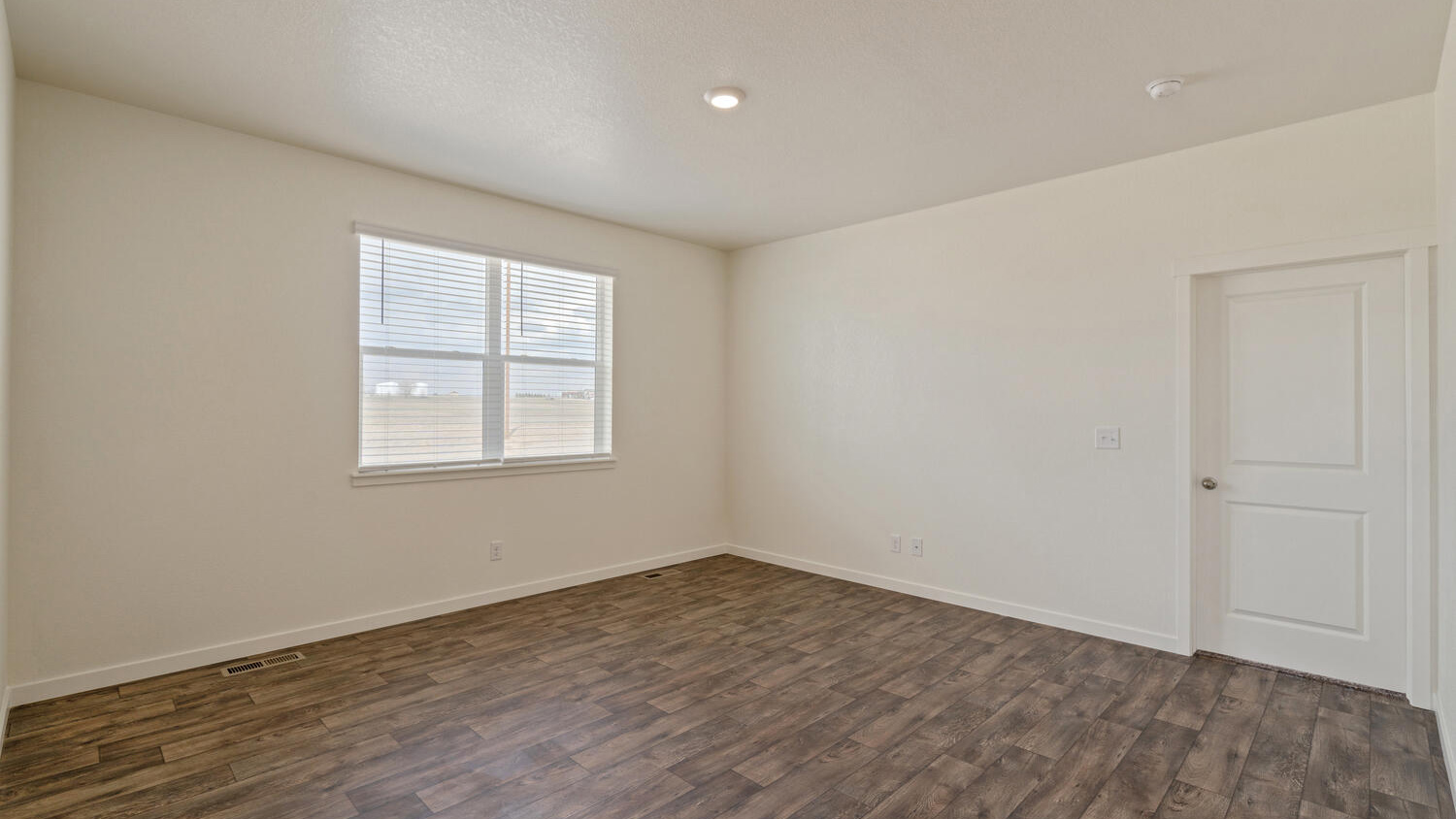 Corner view of great room with large window and door to primary bedroom