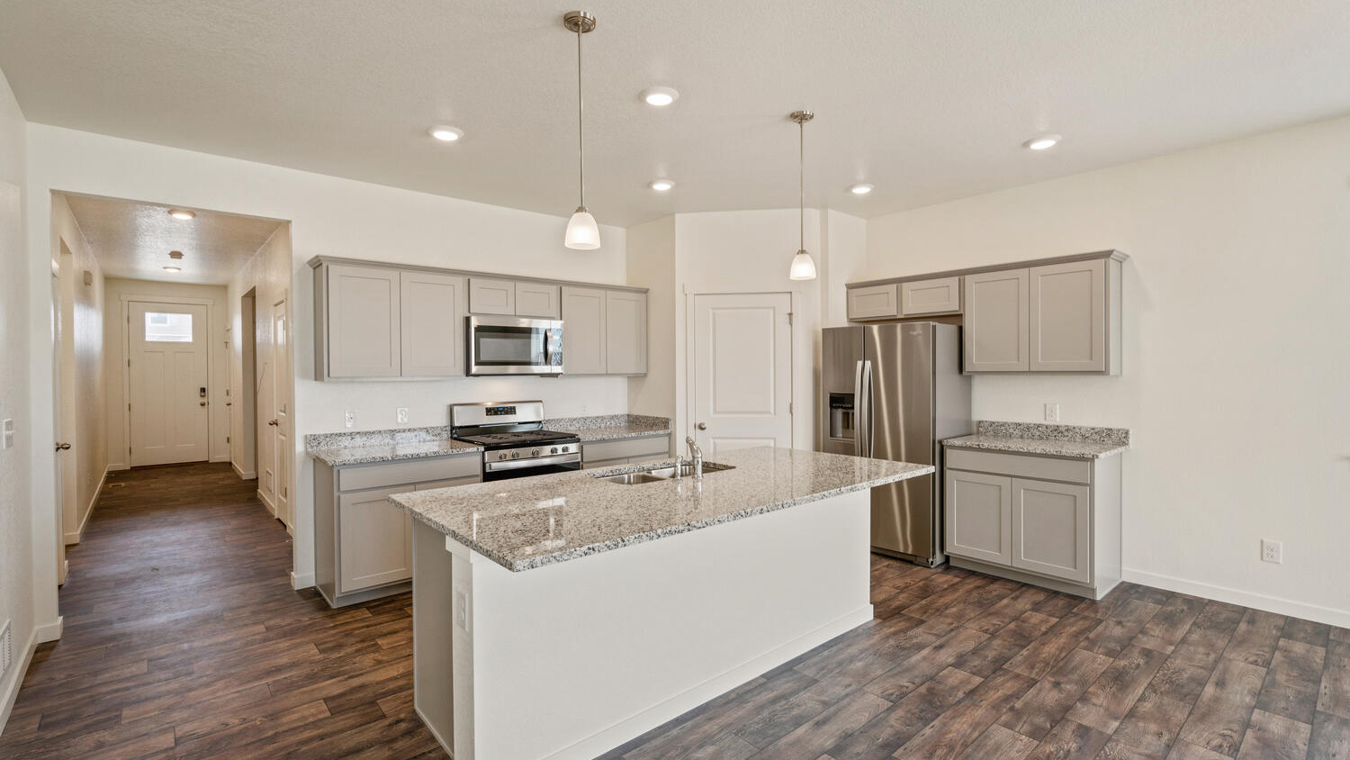 Kitchen showing large center island with granite countertops, pendant lighting, premium cabinetry, and pantry