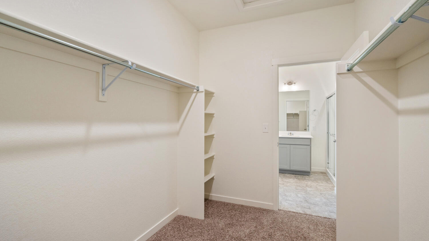 Spacious walk-in closet in primary bedroom suite with built-in shelving