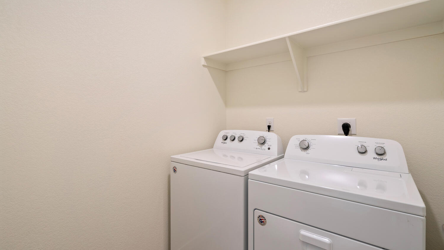 Centrally located laundry room with full washer/dryer hookups and built-in shelf