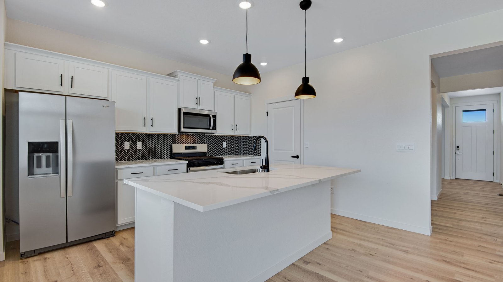 large kitchen island with black pendants in new home by D.R. Horton