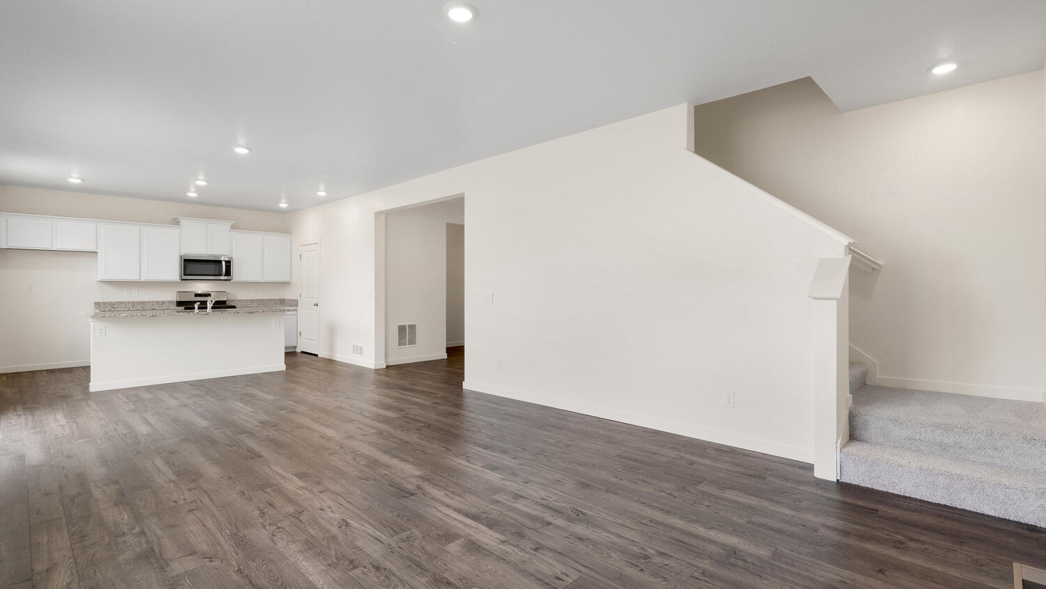 Main living area showing kitchen, great room, and stairwell to upper floor