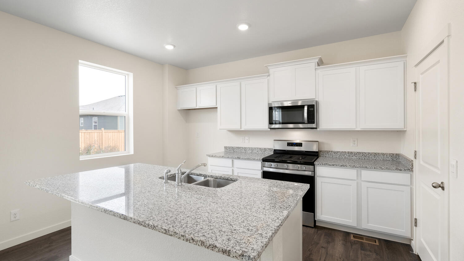 Angled view of kitchen showing ample storage space and lighting from LED fixtures and window
