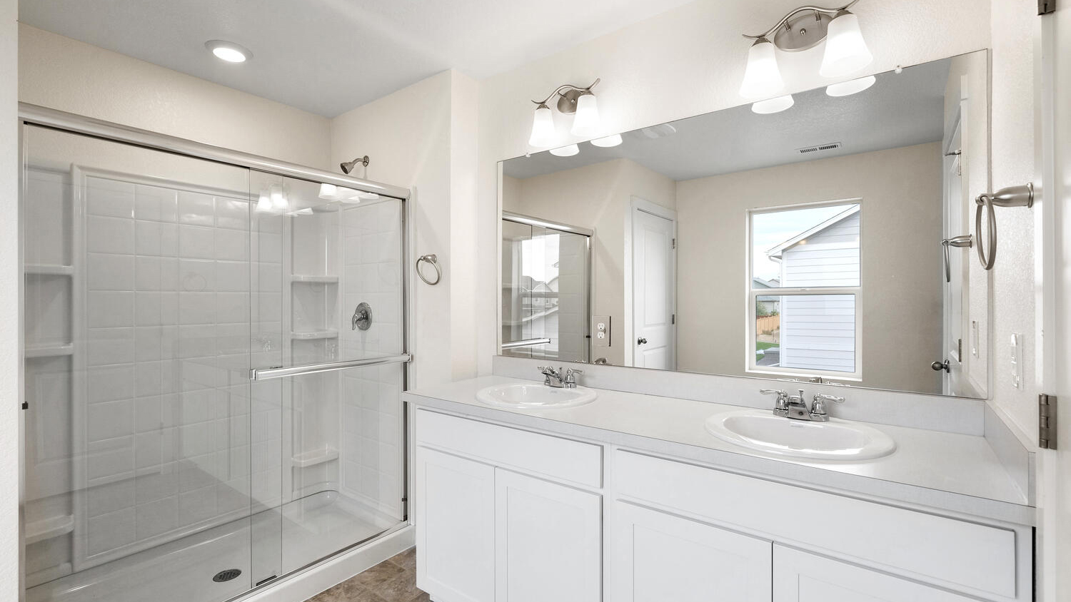 Private bathroom in primary bedroom suite featuring dual sinks, chrome fixtures, and step-in shower