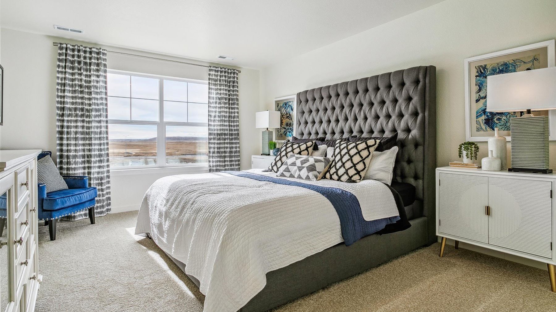 Primary bedroom suite with large window and plush carpeting