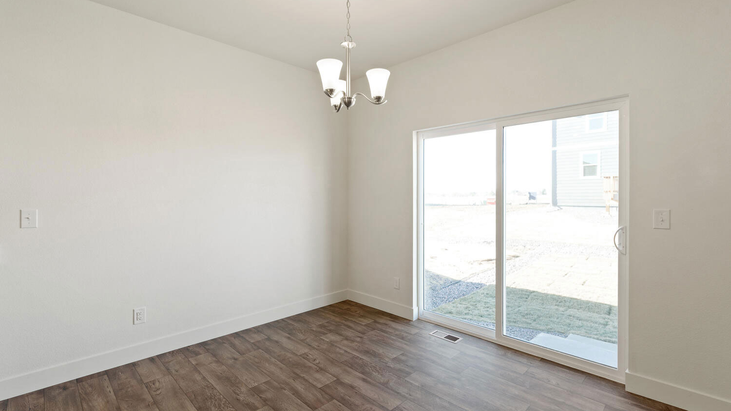 Dining nook with suspended light fixture and sliding patio door