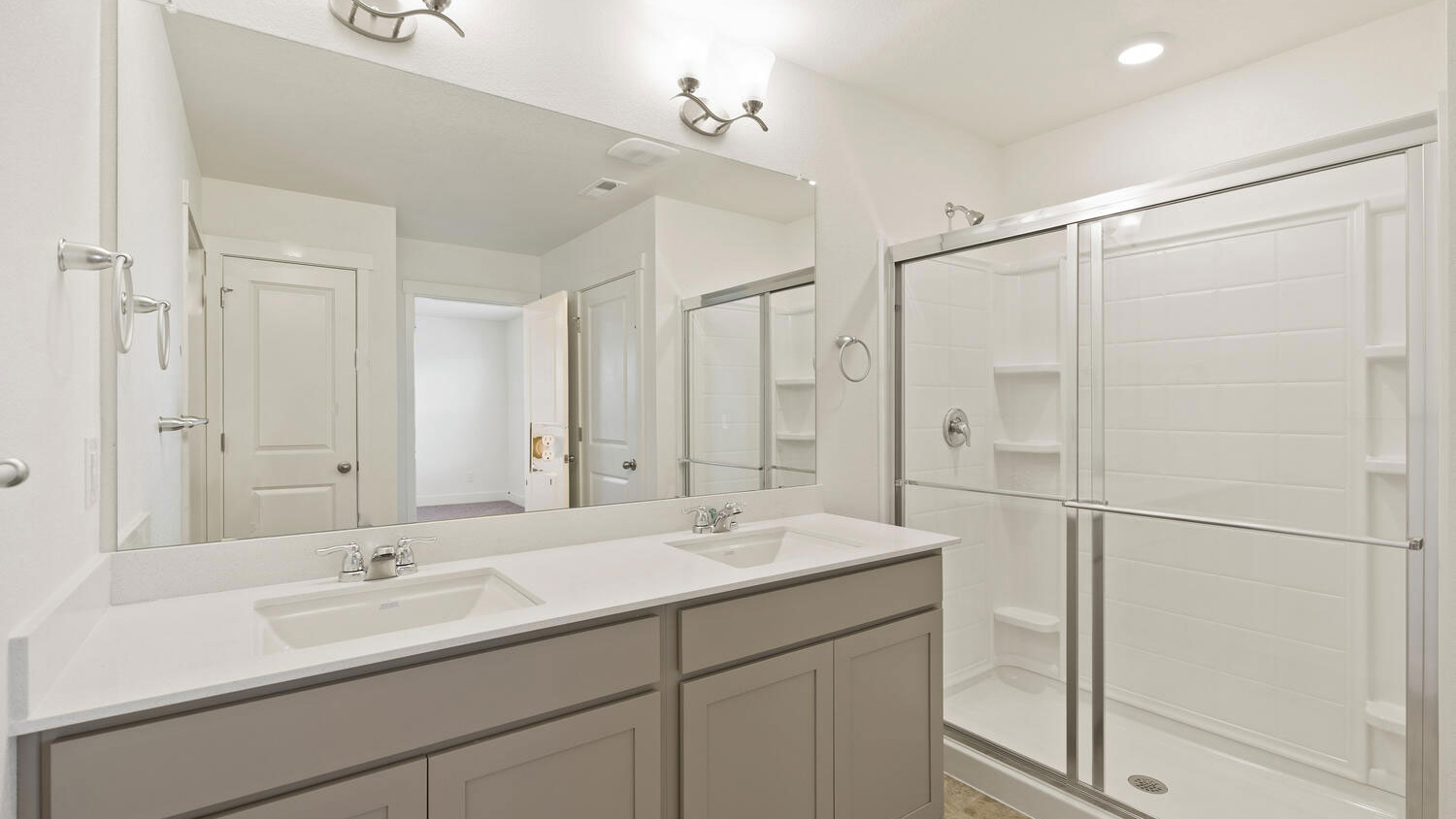 Double vanity sinks, step-in shower, and chrome fixtures in primary suite private bathroom