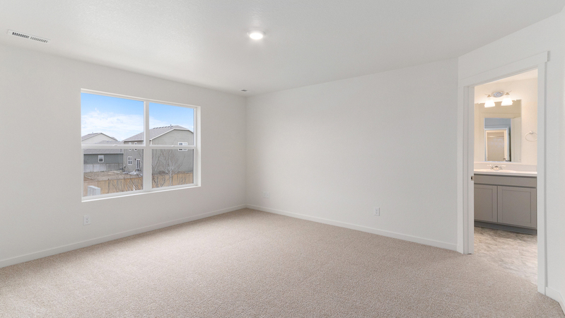Primary bedroom view with large window and private bathroom suite