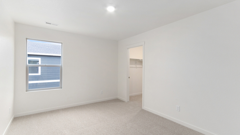 Secondary bedroom showing large window and walk-in closet with built-in shelving