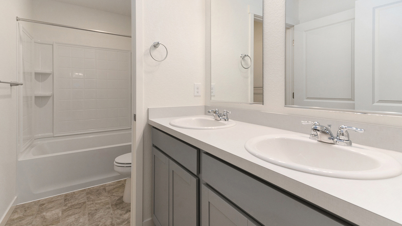 Additional upper floor bathroom near stairwell with bathtub and dual sinks