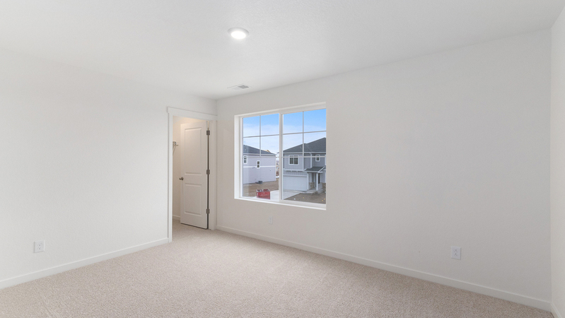 Secondary bedroom showing large window, ample lighting, and walk-in closet