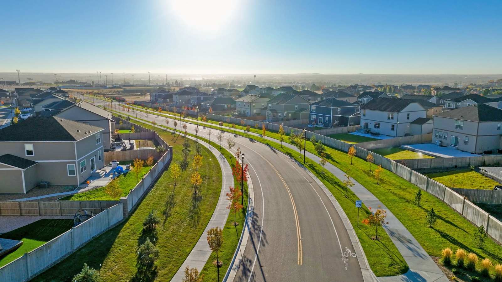 Tree-lined meadowlark parkway that bisects the community with morning sun glinting off of the ponds of adjacent golfcourse