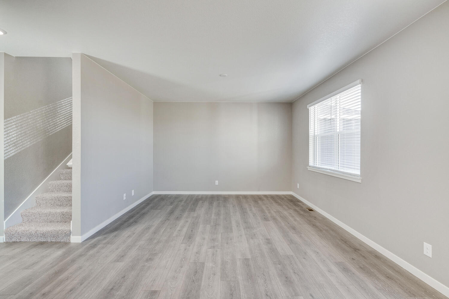 Great room with view of soaring ceilings and adjacent carpeted stairwell