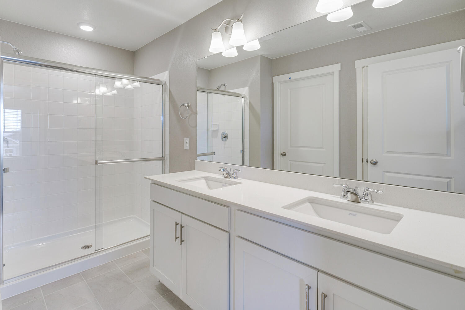En suite bathroom with dual-sink vanity, granite countertops, chrome faucets and walk-in shower