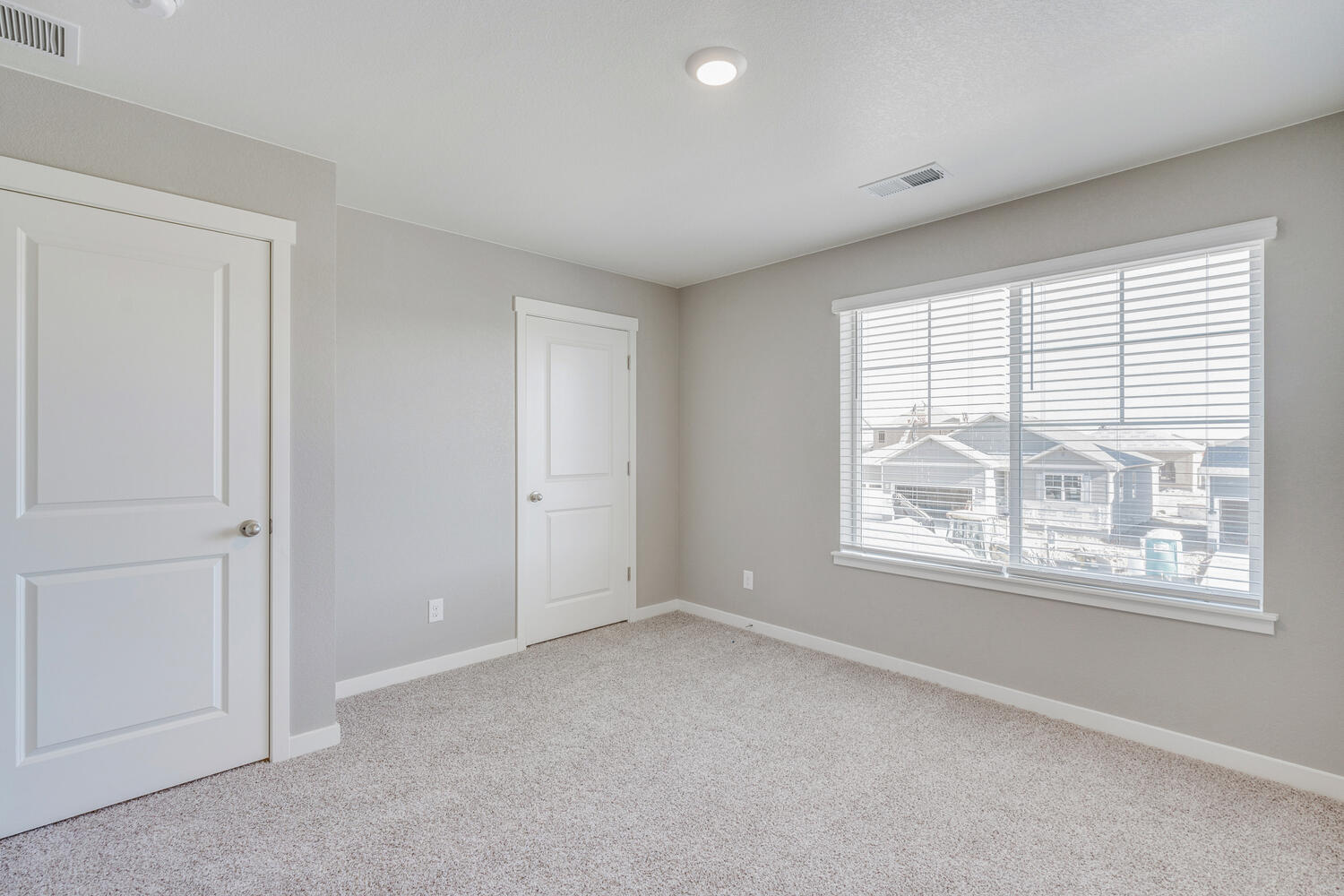 Bedroom 4 with front-facing window,  ceiling mounted heating units, showcasing overhead lighting and closet.