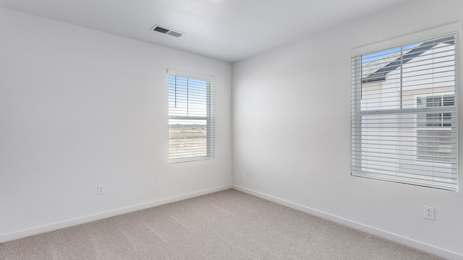 Secondary bedroom with large windows and spacious closets in new D.R. Horton home in Aurora, Colorado