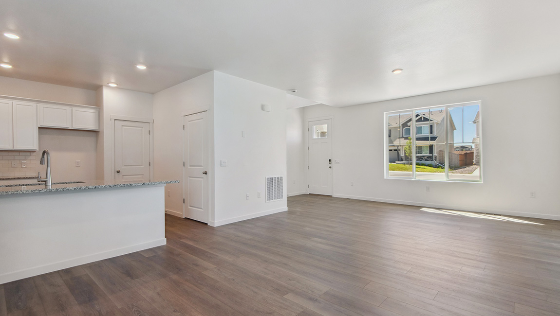 From the dining room, this view shows the great room at the front of the home, with gridded windows, foyer and entry door