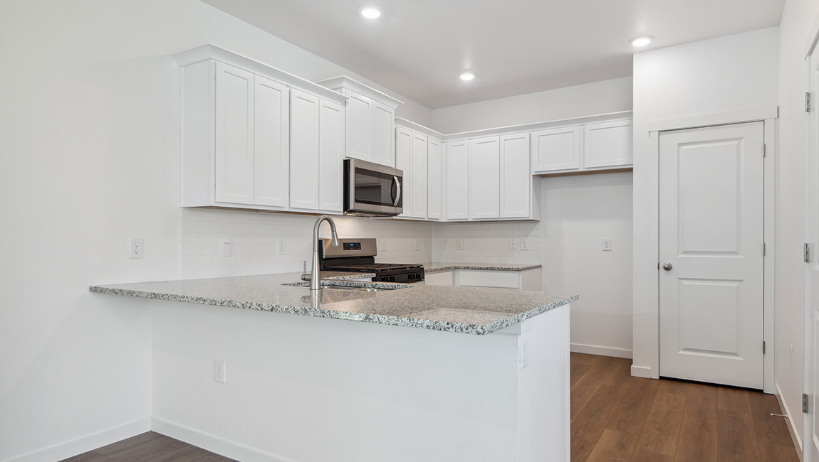 From the dining room, this view shows the great room at the front of the home, with gridded windows, foyer and entry door