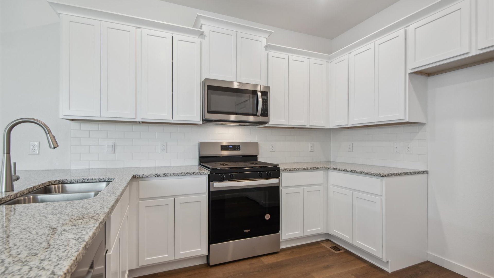 Douglas kitchen showcasing extensive counterspace with under-mount sink, white cabinetry and stainless steel appliances